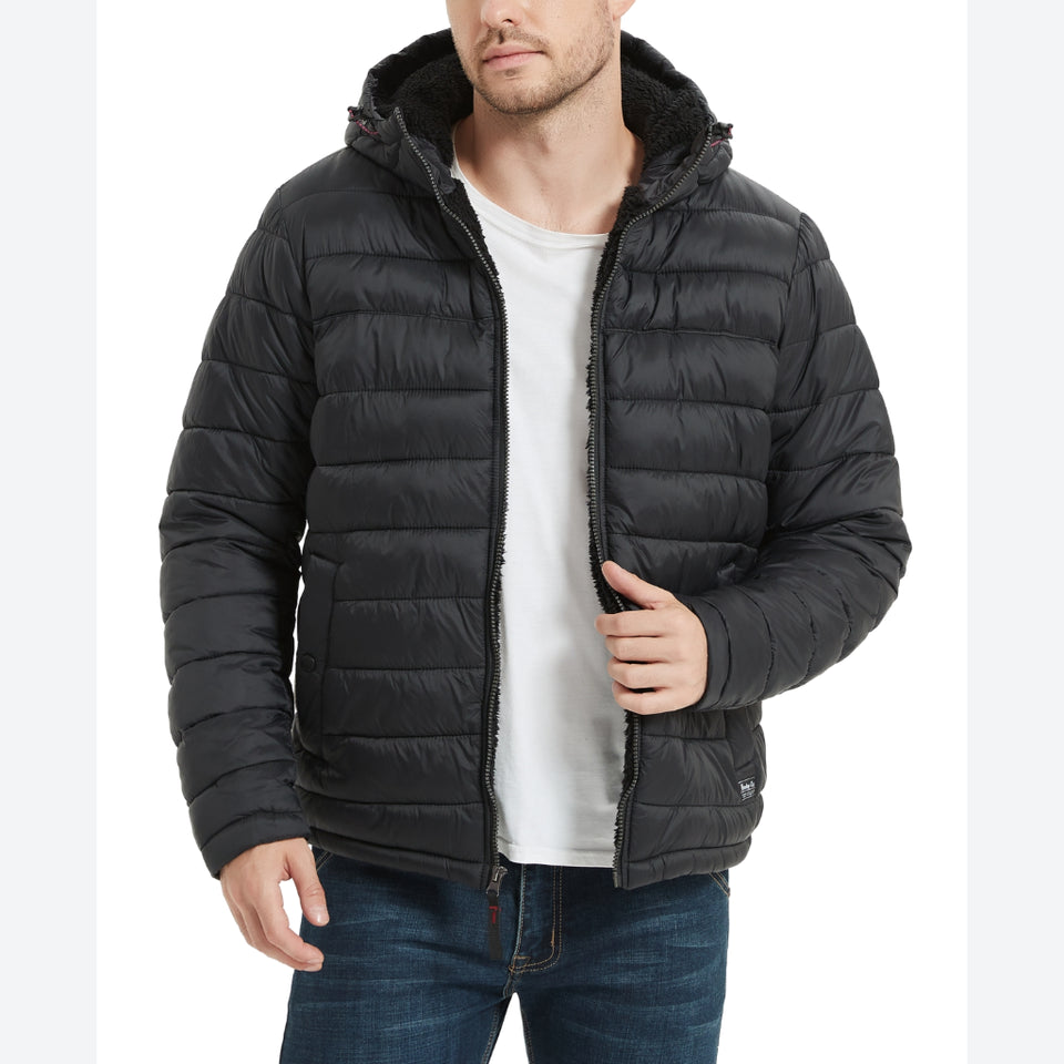 A man wearing a black hooded puffer jacket with a white t-shirt and blue jeans, shown from the chin down against a plain white background.