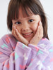 Child wearing a purple robe with butterfly patterns, smiling and posing with hands on face.