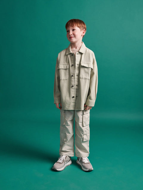Child wearing a beige jacket and pants on a green background