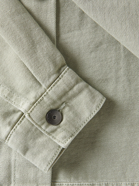 Close-up of a button on a light green denim jacket