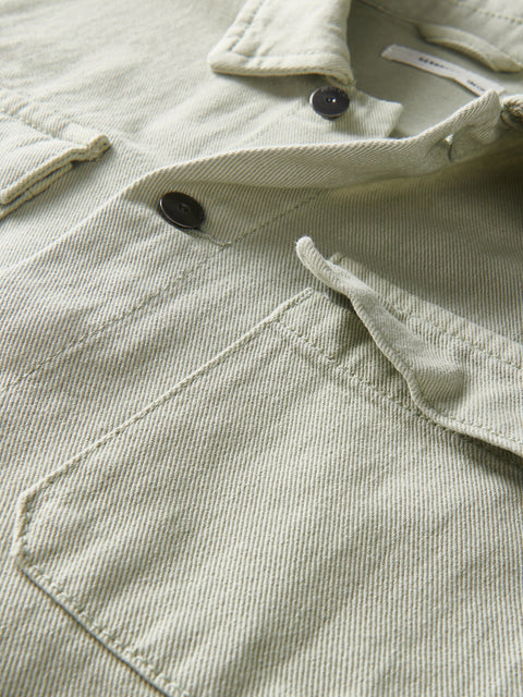 Close-up of a light green corduroy jacket with buttons and stitching details.
