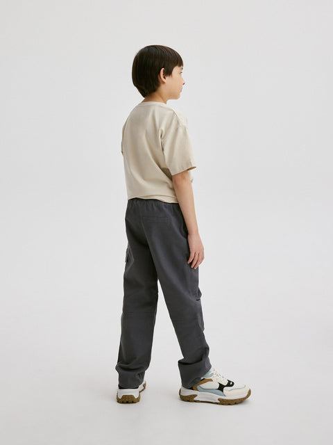 Child wearing a beige shirt and gray pants on a white background
