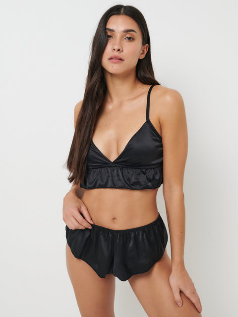 Woman wearing a black satin bikini set on a white background