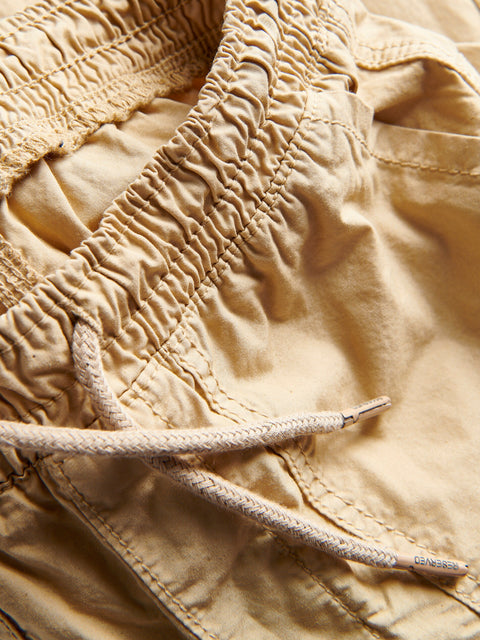 Close-up of beige pants with a drawstring, focusing on texture and material.