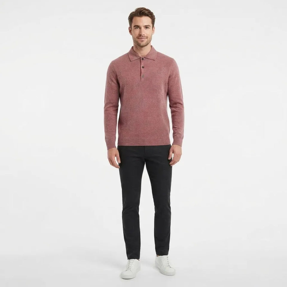 A man modeling a long-sleeve polo shirt in a dusty rose color, paired with black trousers and white sneakers, against a plain white studio background.