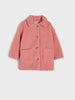 Pink teddy coat with gold buttons on a light gray background