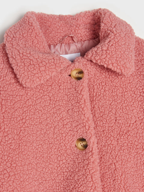 Close-up of a pink textured garment with gold buttons on a white background