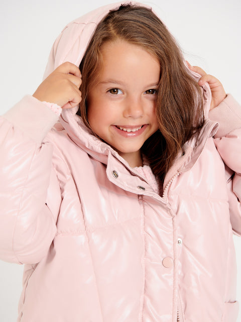 Young girl wearing a pink puffer jacket on a white background