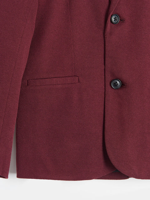 Close-up of a burgundy blazer with two buttons on a white background
