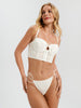 Woman wearing a white lace bikini against a plain background