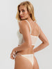 Woman wearing a white lace lingerie set on a plain background