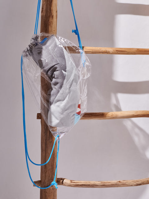 Clear plastic bag with a gray and white pattern hanging from a wooden ladder against a light background