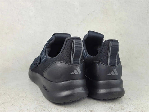 Black Adidas sneakers on a light gray textured background