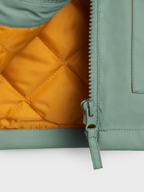 Close-up of a green and mustard yellow quilted jacket with a zipper.