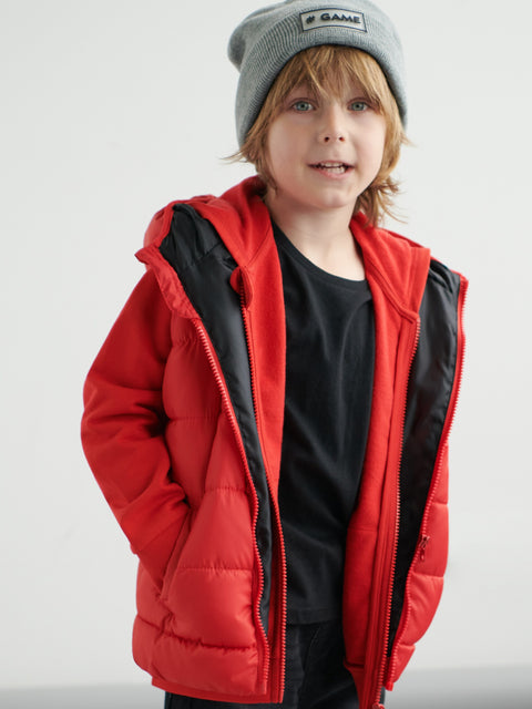 Child wearing a red puffer jacket and gray beanie on a white background