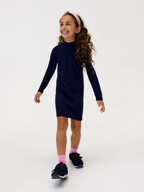 Young girl wearing a navy dress with long sleeves on a white background