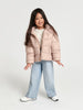 Young girl wearing a light pink puffer jacket on a white background