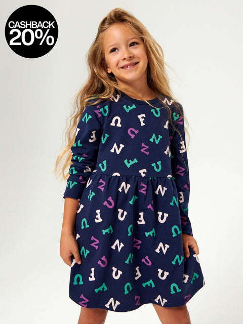 Young girl wearing a navy dress with colorful letter pattern on a white background