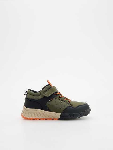 Green and black sneaker with orange accents on a white background