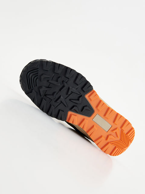 Close-up of a shoe sole with black and orange tread pattern on a white background