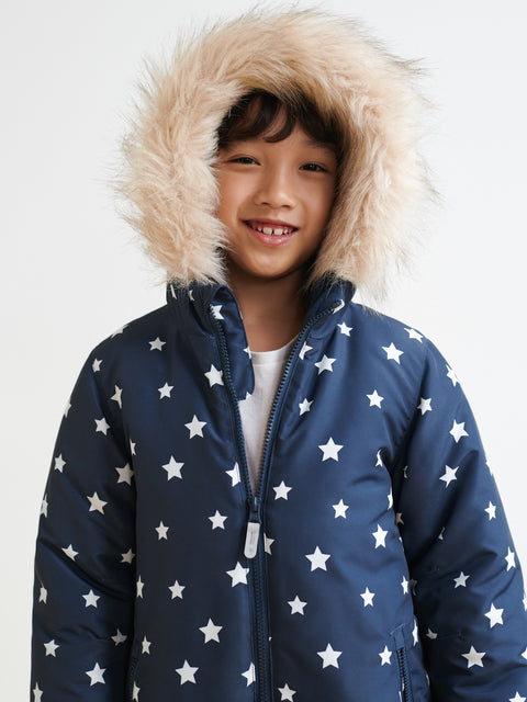 Child wearing a navy blue jacket with white star patterns and a fur-lined hood on a light gray background