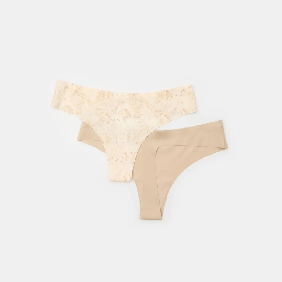 Two pairs of women's thong underwear laid flat on a light gray background. The top pair is a light beige color with a delicate floral lace pattern, and the bottom pair is a solid nude beige.