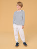 Child wearing a striped shirt and white pants on a beige background