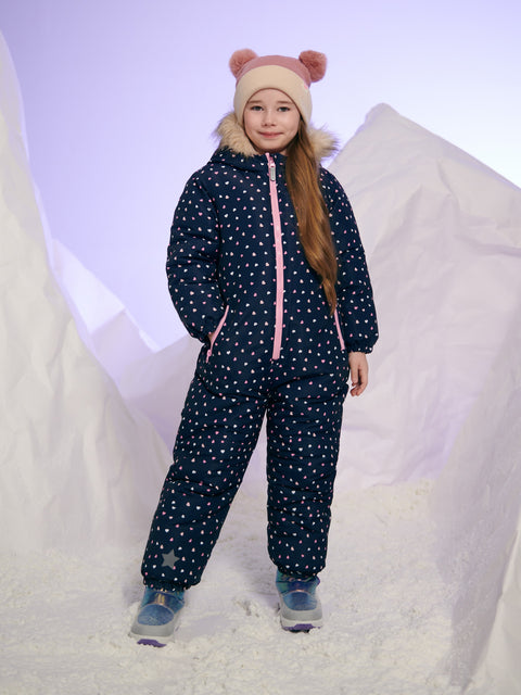 Child wearing a navy blue snowsuit with white star pattern and pink accents on a snowy background