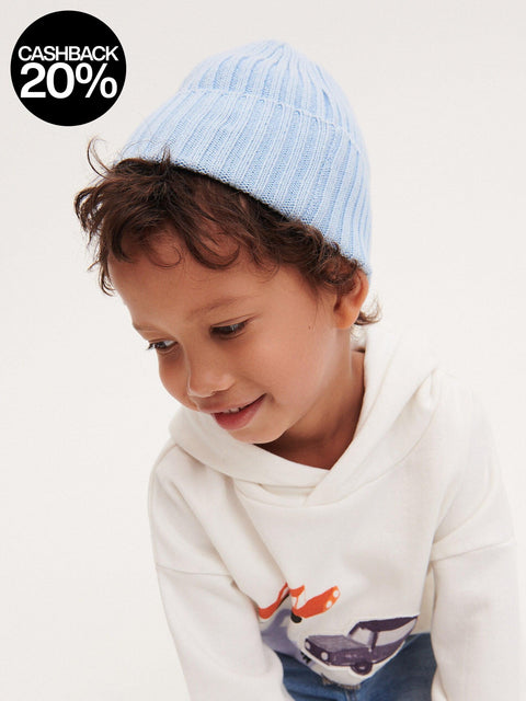 Child wearing a blue striped beanie and white hoodie with airplane design.