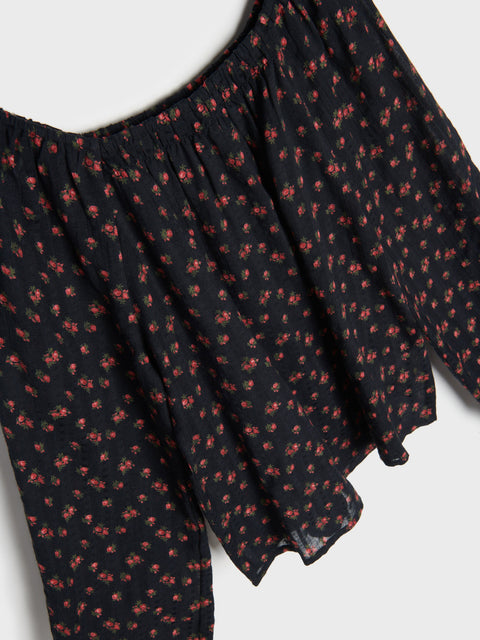 Black off-shoulder top with red floral pattern on a white background