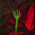 A glowing neon green plastic skeleton hand hanging from a chain, set against a dark background with red lighting and fake cobwebs.