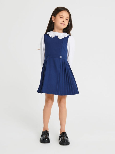Young girl wearing a blue dress with a white collar on a white background
