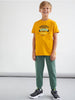 Child wearing a yellow t-shirt with text and green pants on a white background