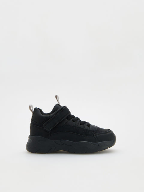 Black sneaker with velcro straps on a white background