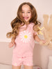 Young girl in pink pajamas with a daisy design, holding a teddy bear.
