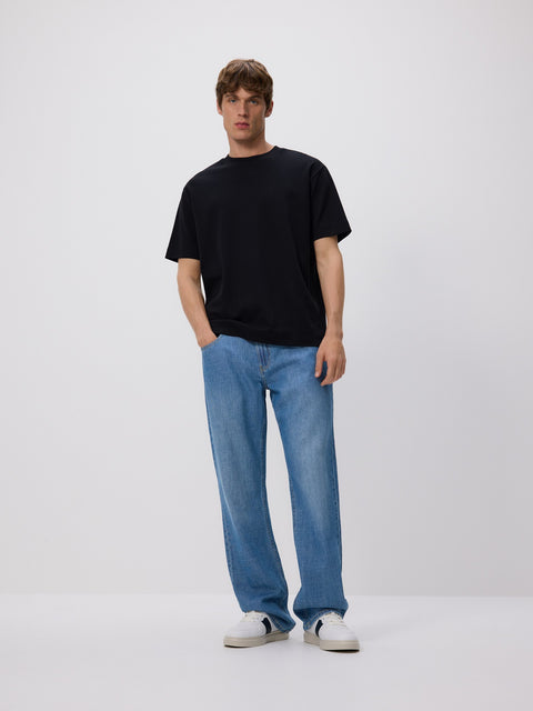 Person wearing a black t-shirt and blue jeans on a white background
