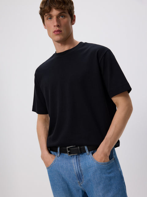 Man wearing a black t-shirt and blue jeans on a white background