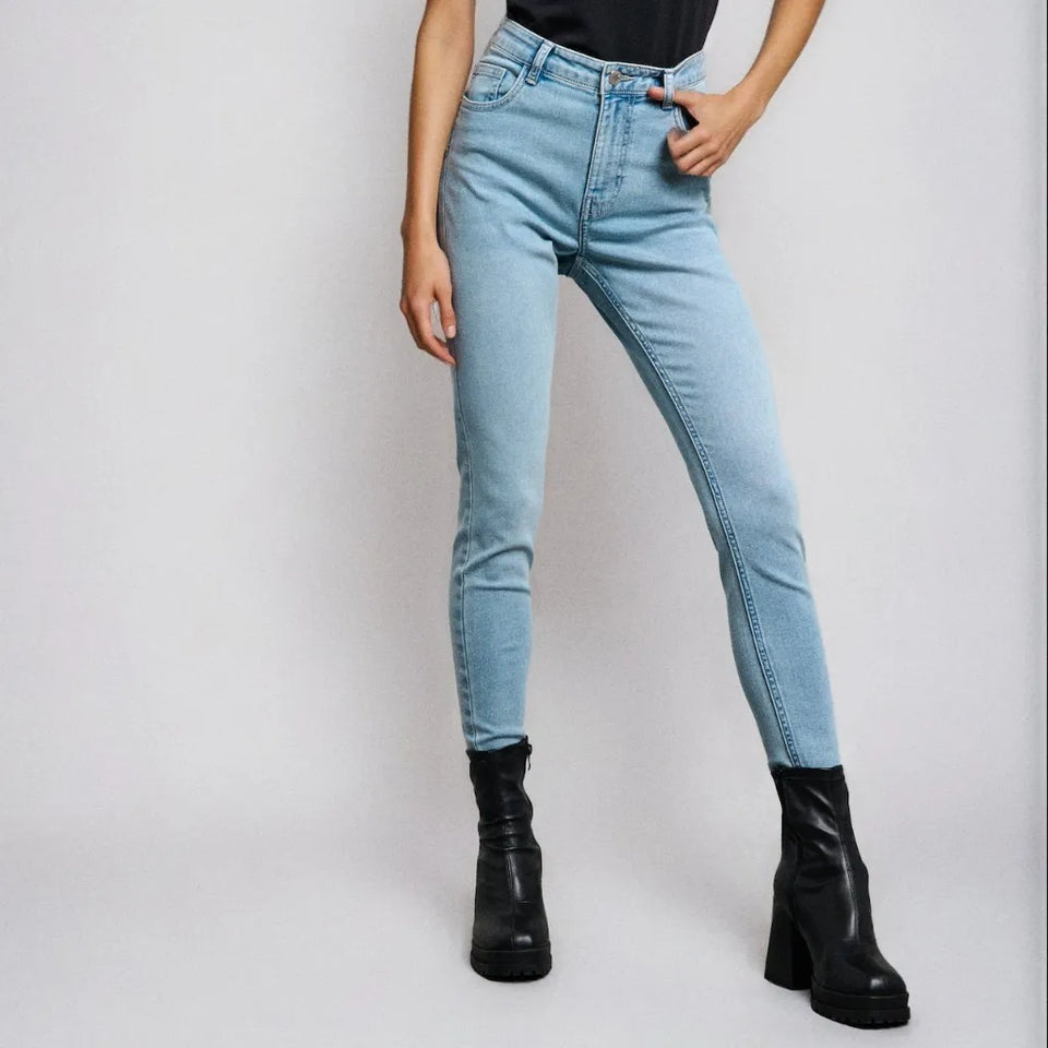 A model wearing light-wash blue skinny jeans with black platform ankle boots, shown from the waist down against a light gray studio background.