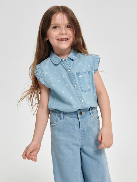 Young girl wearing a light blue denim outfit with a white background