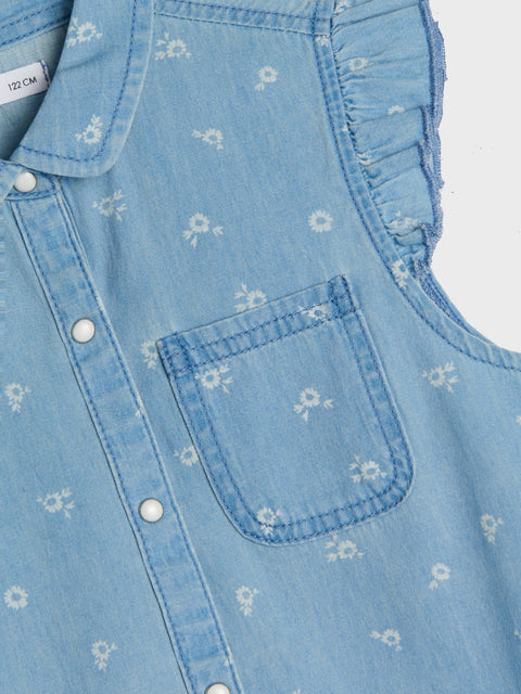 Close-up of a blue denim dress with floral patterns and button details.