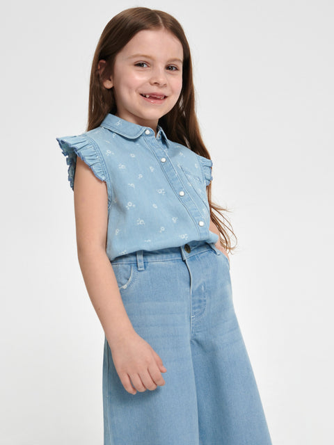Young girl wearing a light blue denim outfit with a white background