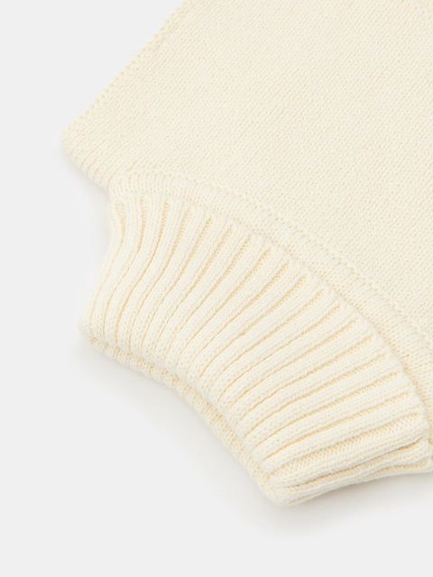 Close-up of a cream-colored knitted sweater on a light gray background