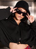 Person wearing a black outfit with sunglasses and a hat in an indoor setting