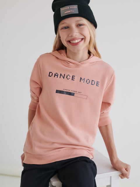 Child wearing a pink 'Dance Mode' hoodie and black beanie on a white background