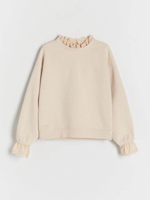 Beige sweatshirt with ruffled collar on a light gray background