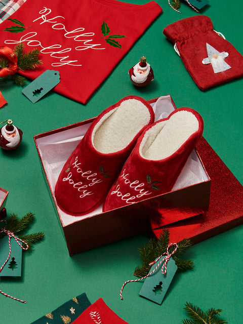 Red slippers with 'Holly Jolly' text on a green background