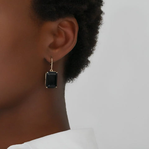 Black rectangular gemstone earring on a model's ear against a neutral background