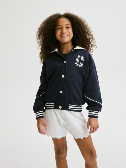 Child wearing a navy varsity jacket with a white 'C' logo on a white background