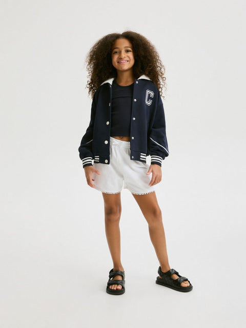 Child wearing a navy varsity jacket with a letter 'C' on a white background
