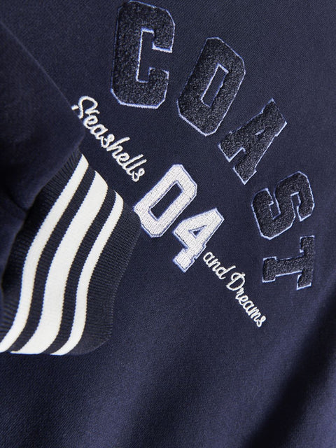 Navy blue jacket with 'Coast 04' and 'Seashells and Dreams' text on a dark background